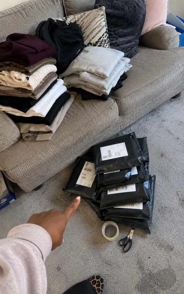 Rochelle's Sunday reselling batch: clothes folded and sorted on the sofa, parcels packed and labelled for the post.