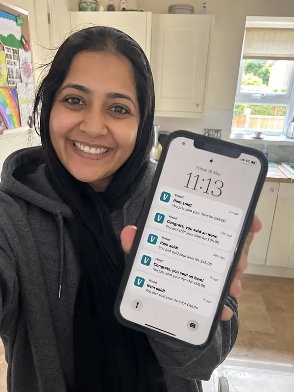 Hibi from Liverpool, smiling in her kitchen and holding up her phone: five Vinted 'Item sold' notifications from one morning, £35 to £50 each.